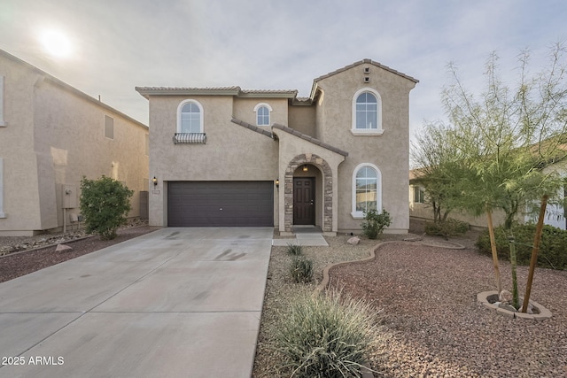 mediterranean / spanish house featuring a garage, concrete driveway, a tiled roof, and stucco siding