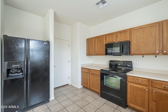 kitchen featuring light tile patterned flooring, visible vents, light countertops, brown cabinets, and black appliances