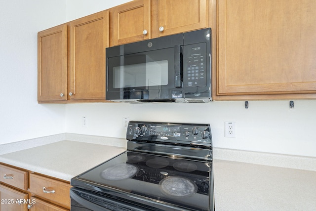 kitchen with black appliances, brown cabinetry, and light countertops