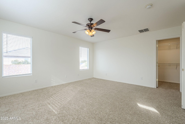 unfurnished bedroom with a spacious closet, carpet, visible vents, and baseboards