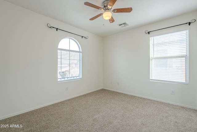 spare room with baseboards, carpet floors, visible vents, and a ceiling fan