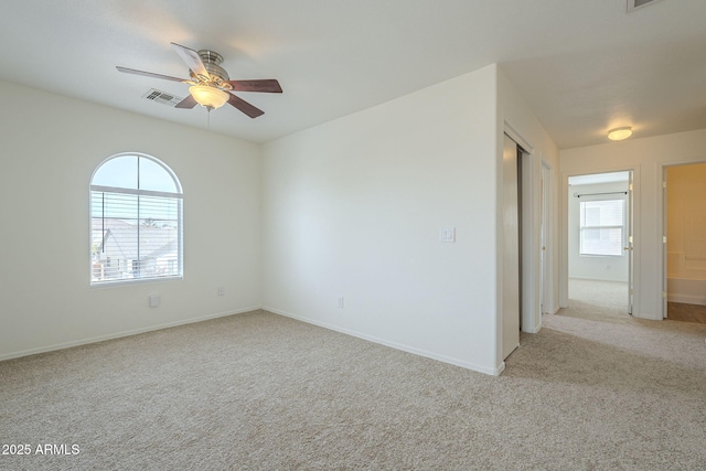 spare room featuring carpet, visible vents, ceiling fan, and baseboards