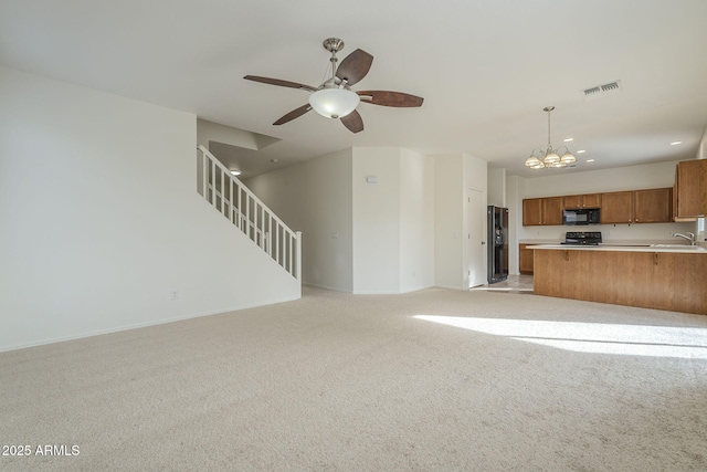 unfurnished living room with ceiling fan with notable chandelier, light carpet, a sink, visible vents, and stairs