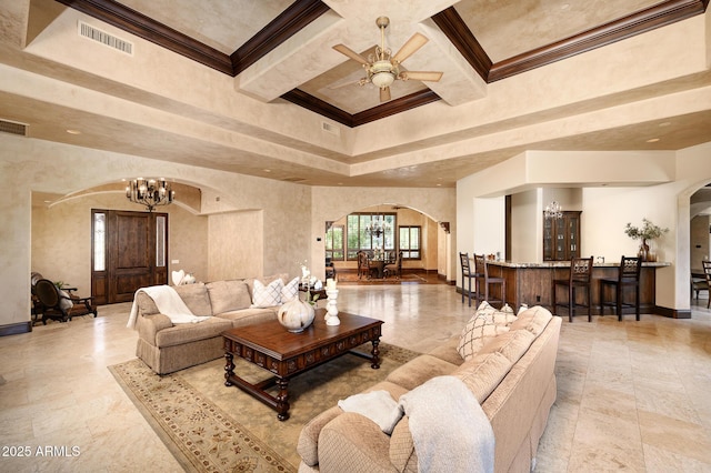 living area featuring ceiling fan with notable chandelier, visible vents, baseboards, arched walkways, and ornamental molding