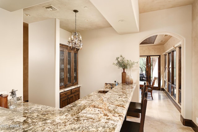 bar featuring a sink, visible vents, arched walkways, decorative light fixtures, and a chandelier
