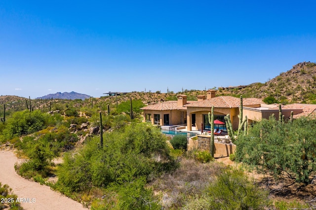 back of house with a mountain view, stucco siding, and a chimney