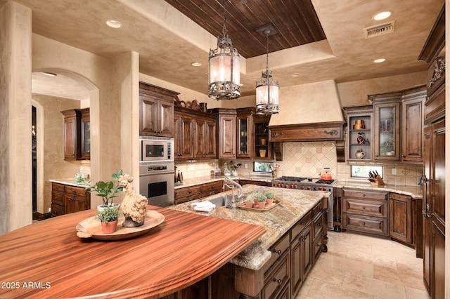 kitchen featuring dark brown cabinets, a sink, backsplash, appliances with stainless steel finishes, and butcher block counters