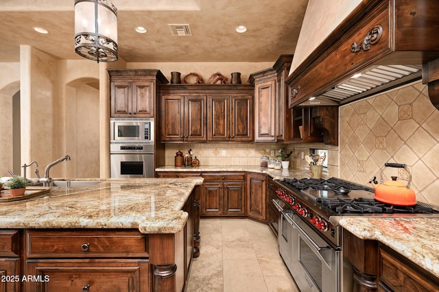 kitchen featuring a sink, visible vents, arched walkways, custom range hood, and appliances with stainless steel finishes