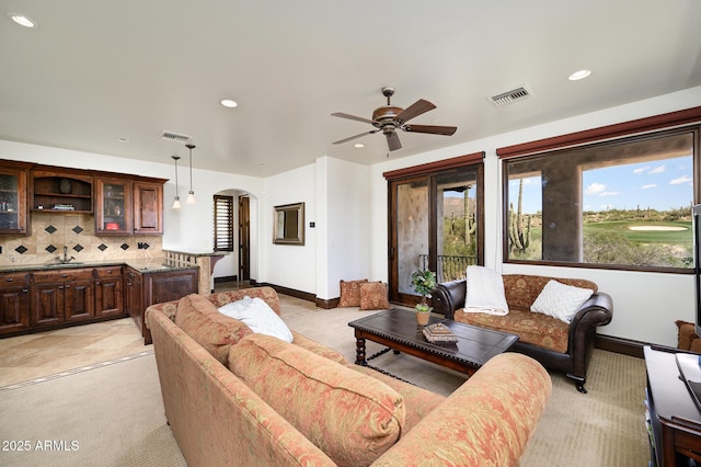 living area with visible vents, a ceiling fan, arched walkways, and recessed lighting