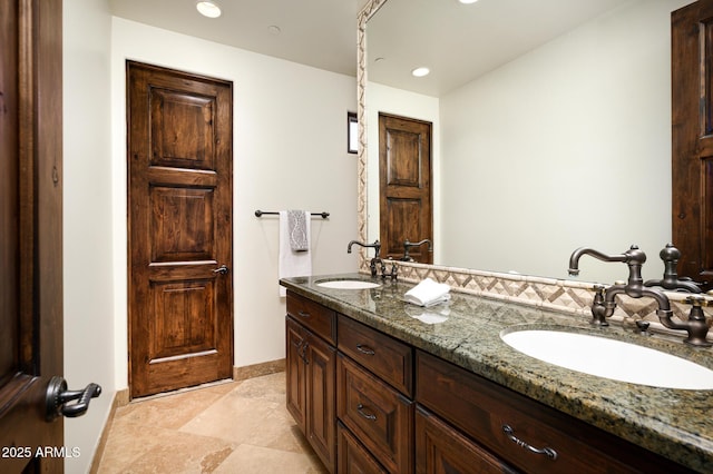 full bath with a sink, double vanity, baseboards, and recessed lighting