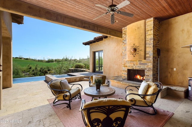 view of patio with an outdoor stone fireplace and ceiling fan