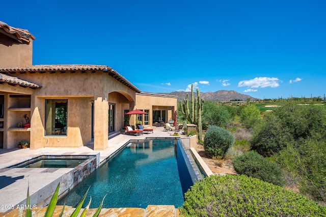 view of swimming pool featuring a mountain view, a patio, and a pool with connected hot tub