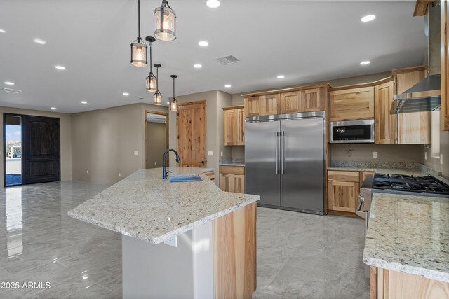 115 Ironwood Pl, Wickenburg, AZ 85390 - kitchen with wall chimney exhaust hood, stainless steel appliances, a sink, a center island with sink, and visible vents