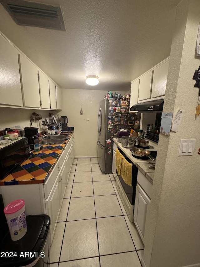 kitchen with a textured ceiling, white electric range oven, white cabinetry, and light tile patterned flooring