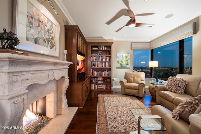 living room with dark wood-style flooring, ornamental molding, and a ceiling fan