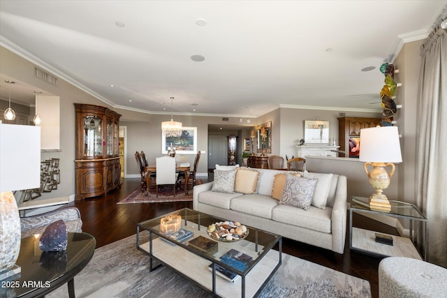 living room featuring visible vents, ornamental molding, hardwood / wood-style flooring, baseboards, and a chandelier