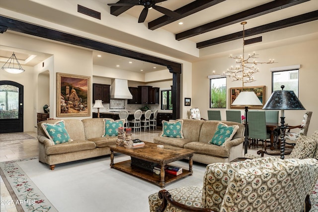 living room featuring ceiling fan with notable chandelier and beamed ceiling