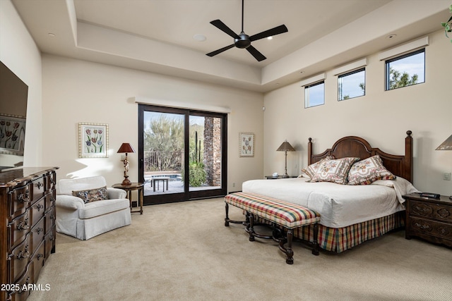 bedroom featuring light colored carpet, a tray ceiling, ceiling fan, access to exterior, and a high ceiling