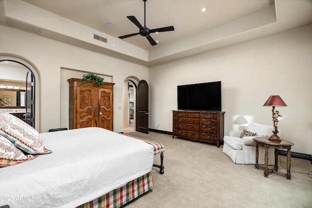 carpeted bedroom with a raised ceiling and ceiling fan