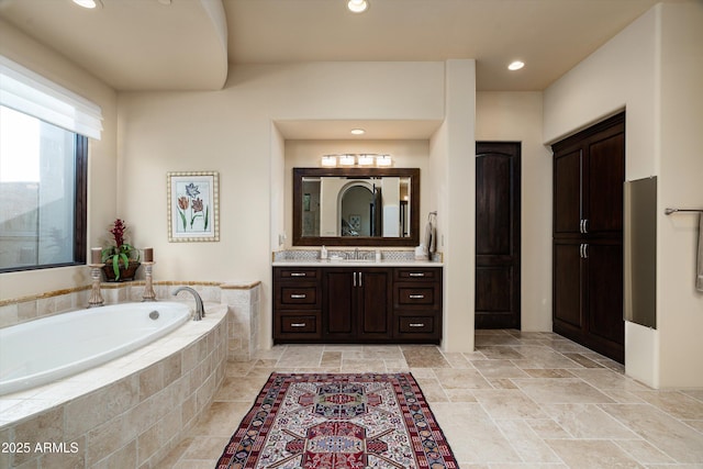 bathroom with vanity and a relaxing tiled tub