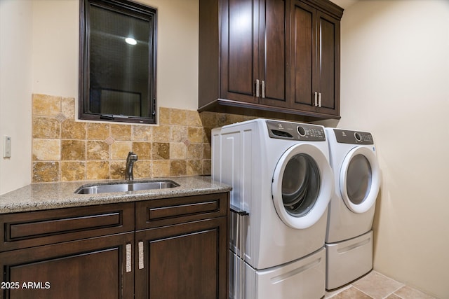 washroom with sink, washing machine and dryer, and cabinets