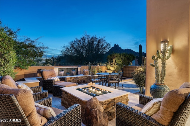 patio terrace at dusk featuring a mountain view and an outdoor living space with a fire pit