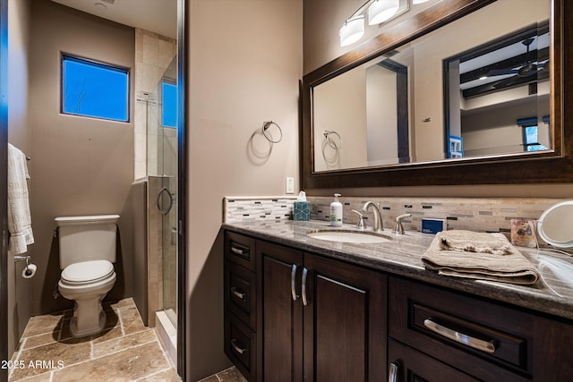 bathroom with tasteful backsplash, vanity, a shower with door, and toilet