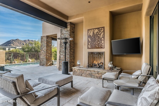 view of patio featuring a mountain view, a fenced in pool, and an outdoor stone fireplace