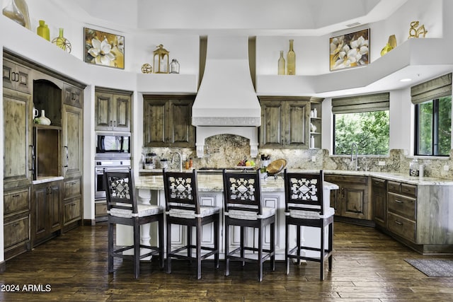 kitchen featuring custom exhaust hood, tasteful backsplash, a center island, and stainless steel oven