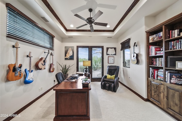 carpeted office space featuring a raised ceiling, ornamental molding, and ceiling fan