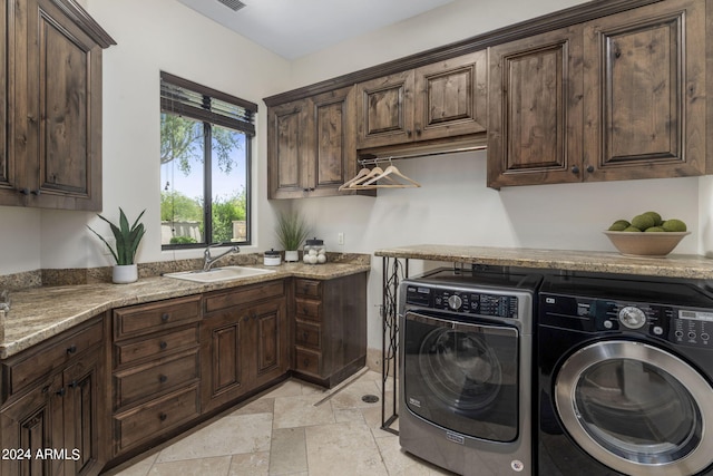 laundry room with cabinets, washing machine and clothes dryer, and sink