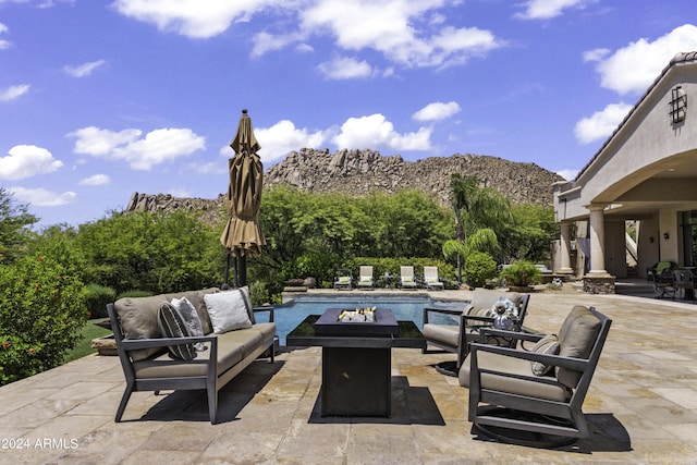 view of patio with a mountain view and an outdoor living space with a fire pit