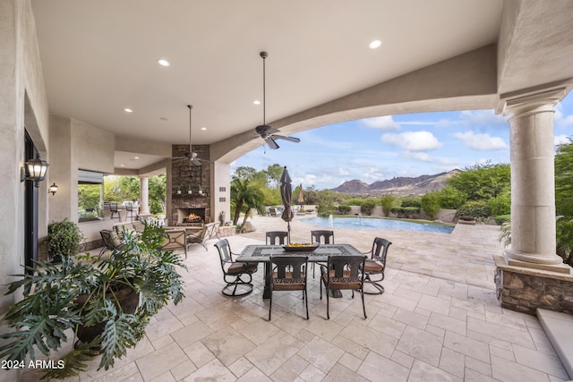 view of patio featuring ceiling fan, a water and mountain view, and an outdoor stone fireplace