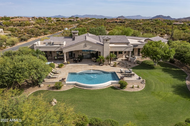 view of swimming pool featuring a patio, a mountain view, and a yard