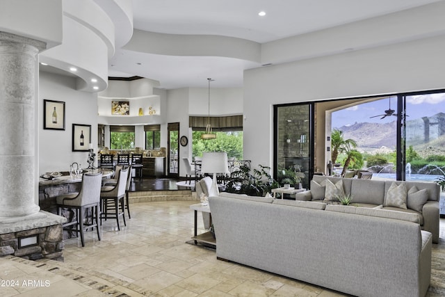 living room featuring a towering ceiling, decorative columns, and ceiling fan