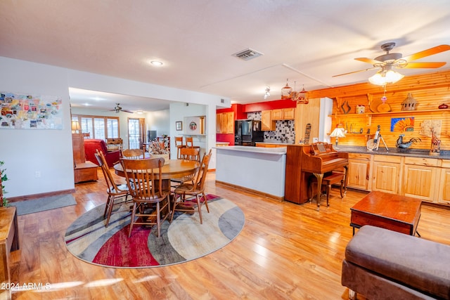 dining space featuring ceiling fan, wood walls, and light wood-type flooring