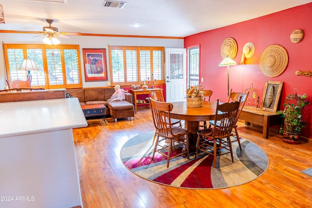 dining space featuring light wood-type flooring, ceiling fan, and crown molding