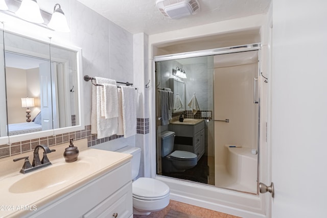 bathroom featuring vanity, toilet, a textured ceiling, tasteful backsplash, and an enclosed shower