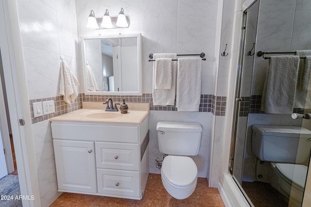 bathroom with backsplash, toilet, vanity, a shower with shower door, and tile walls