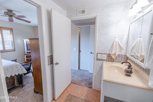 bathroom with ceiling fan, vanity, and tile walls