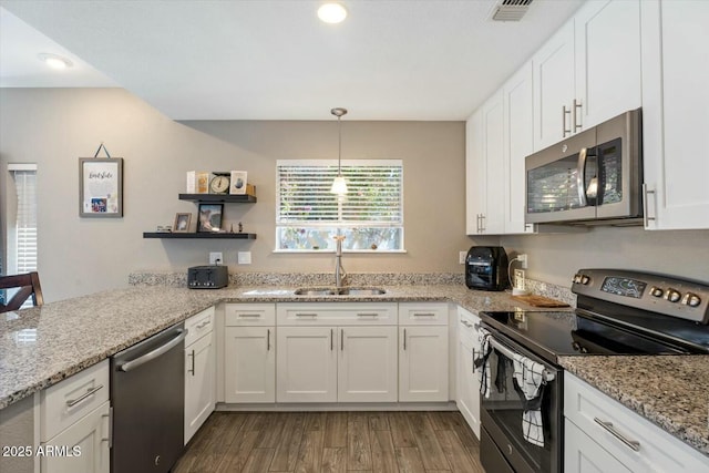 kitchen with decorative light fixtures, visible vents, appliances with stainless steel finishes, white cabinets, and a sink