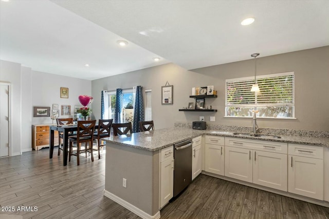 kitchen featuring dark wood-type flooring, white cabinets, a sink, dishwasher, and a peninsula