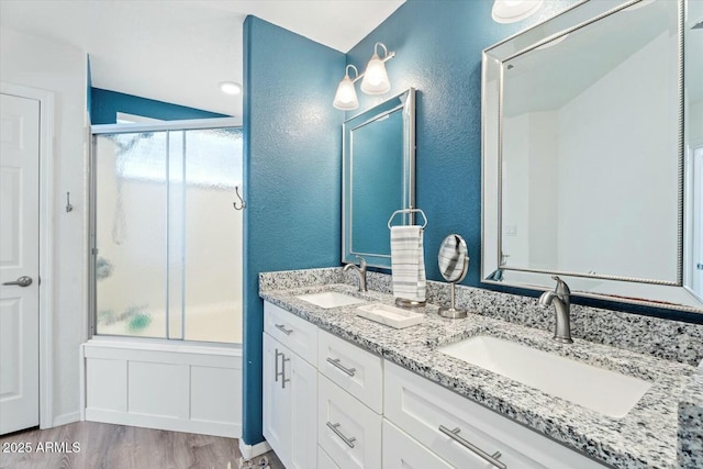 full bathroom with plenty of natural light, enclosed tub / shower combo, a sink, and wood finished floors