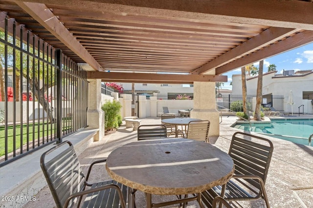 view of patio with outdoor dining area, fence, and a community pool