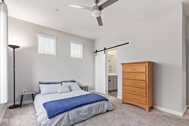 carpeted bedroom with ceiling fan, a barn door, and connected bathroom