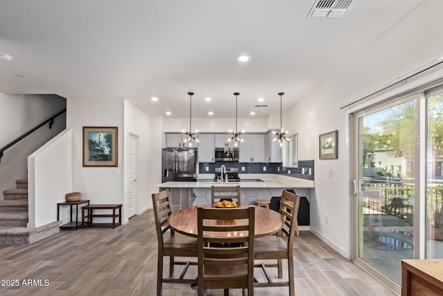 dining room with light hardwood / wood-style floors, a notable chandelier, and sink