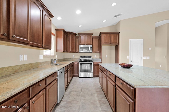 2620 E Rustling Oaks Ln, Phoenix, AZ 85024 - kitchen featuring appliances with stainless steel finishes, a sink, vaulted ceiling, light stone countertops, and a center island