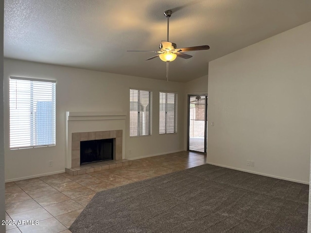 unfurnished living room featuring ceiling fan, vaulted ceiling, a fireplace, and tile patterned floors