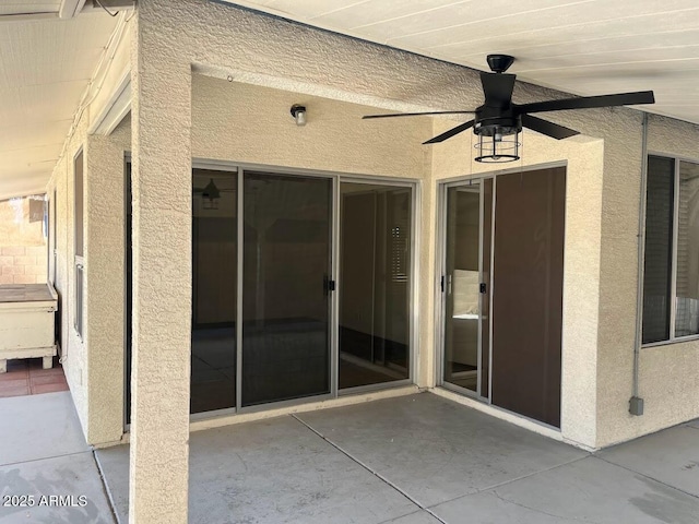 view of exterior entry featuring a patio area, a ceiling fan, and stucco siding