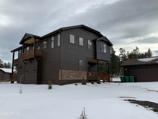 view of snowy exterior with a balcony and a garage